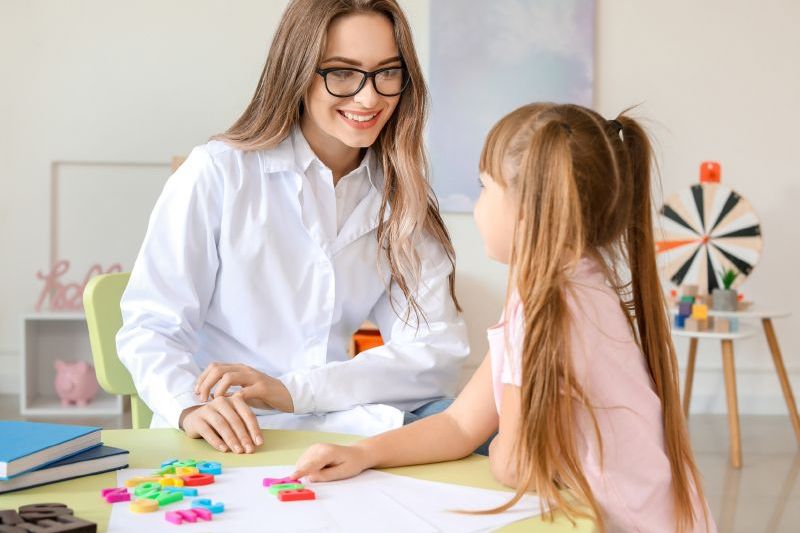 Terapeuta trabajando con una niña con material didáctico Terapeuta trabajando con una niña con material didáctico